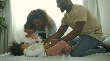 Happy African American Parents with  little daughters playing on the bed in bedroom at home, happy family concept video