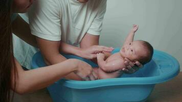 New born having a bath by happy mother and father, family and love concept video