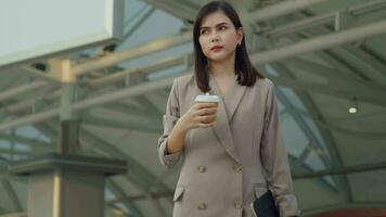 A young beautiful businesswoman is drinking coffee walking  in Modern city , business technology , city lifestyle concept video