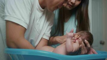 New born having a bath by happy mother and father, family and love concept video