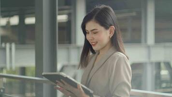 una joven y hermosa mujer de negocios está usando una tableta en una ciudad moderna, tecnología de negocios, concepto de estilo de vida de la ciudad video