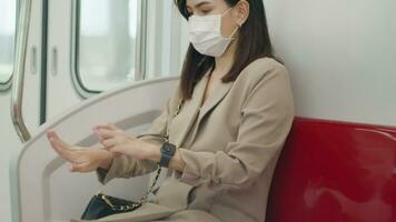 uma jovem mulher é vestindo protetora mascarar pulverização álcool desinfetante em metro trem , covid-19 proteção , segurança transporte , viagem debaixo pandemia conceito . video