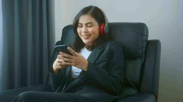 Young relaxing business woman using smartphone and listening to music in modern office. video