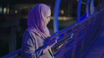 eine junge muslimische geschäftsfrau benutzt nachts einen tablet-computer in der modernen stadt, business-technologie-lifestyle-konzept video