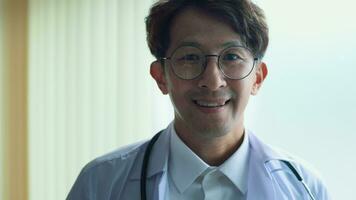 portret van zelfverzekerd glimlachen dokter vervelend wit jas in ziekenhuis video