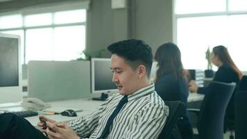 A business man is playing mobile games on his smartphone in office video