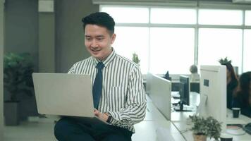 An Asian man is using laptop computer , video calling to business partner in office