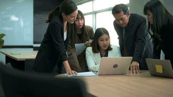 Group of business people looking at computer and discussing in modern office video