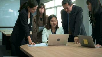 Group of business people looking at computer and discussing in modern office video