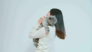 A young woman is holding lovely cat , playing with cat in studio on white background video