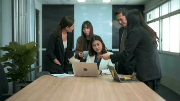 Group of business people looking at computer and discussing in modern office video