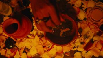 a shaman's hand is inserting incense into a burning jug on an altar offerings during a ritual video