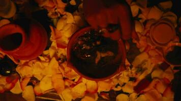 a shaman's hand is inserting incense into a burning jug on an altar offerings during a ritual video