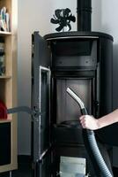 Woman cleaning pellet stove with accessoiries as vacuum cleaner or brush photo