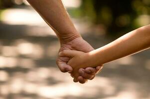 the father's hand held tightly the hand of his little son against the background of green foliage, close-up photo