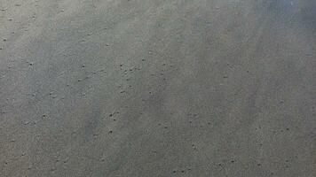 gris playa arena. suave texturizado arena superficie formar alto ángulo. foto