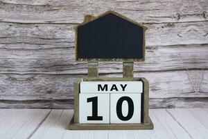 Chalkboard with May 10 date on white cube block on wooden table. photo