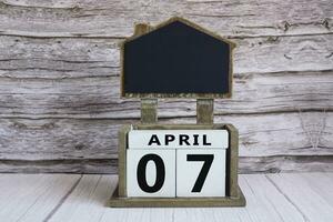 Chalkboard with April 07 date on white cube block on wooden table. photo