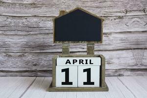 Chalkboard with April 11 date on white cube block on wooden table. photo