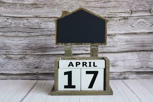 Chalkboard with April 17 date on white cube block on wooden table. photo