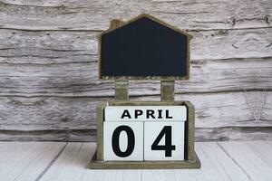 Chalkboard with April 04 date on white cube block on wooden table. photo
