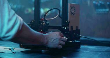 Male engineer making prototype with 3D printer in dark workshop video