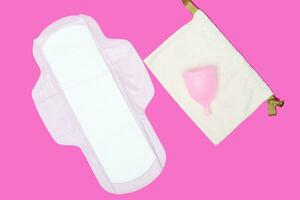 menstrual cup and regular feminine pad on a pink background, top view, copy space. Zero waste concept. Eco-friendly menstrual products photo