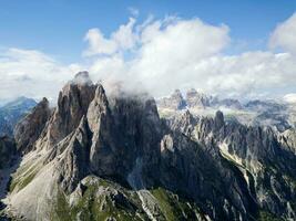 Aerial view of Cadini di Misurina mountains with Tre Cime di Lavaredo mountains in the background during a sunny day with some clouds. Dolomites, Italy. Dramatic and cinematic landscape. photo