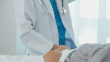 Female doctor in white coat holding hand of senior patient, giving help, comfort, psychological support, empathy at appointment. Elderly medic care, geriatric healthcare concept. Close up video