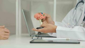 Human head anatomical model on doctor's table over background neurologist analyzing results of MRI scan of patient brain at medical clinic. Diseases of brain, nerves and nervous system video