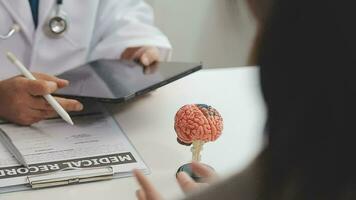 Human head anatomical model on doctor's table over background neurologist analyzing results of MRI scan of patient brain at medical clinic. Diseases of brain, nerves and nervous system video