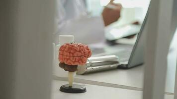umano testa anatomico modello su medico tavolo al di sopra di sfondo neurologo analizzando risultati di mri scansione di paziente cervello a medico clinica. malattie di cervello, nervi e nervoso sistema video