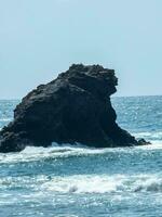 Isolated rock formation in the sea under blue sky. photo