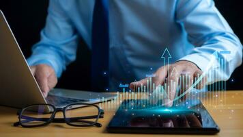 Businessman taps his finger on his tablet to display a graph with arrow for the future growth plan of his organization. finance, management, plan, management, strategy, photo