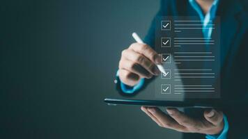 Checklist and filling survey form online. Document management system, DMS. Quality control and accuracy Check, Businessman using tablet online survey filling out, Business performance monitoring. photo