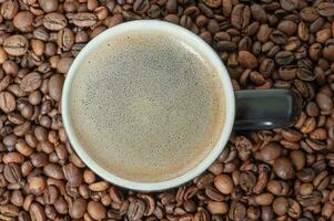 A cup of coffee on the background of roasted coffee beans. Coffee background with espresso. photo