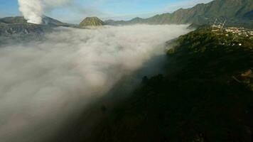 video of flying through the fog in Java. Backdrop of volcanoes.