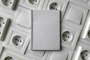 Notepad with copy space on the background of sockets and switches. photo