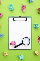 Magnifying glass, clipboard and crumpled colorful stickers around. photo