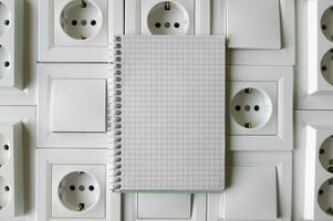 Notepad with copy space on the background of sockets and switches. photo