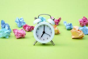 Vintage white alarm clock on a background of crumpled multicolored stickers. photo