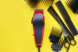 Hair clipper close-up on a yellow background with nozzles of different sizes, scissors and combs. photo