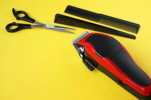 Hair clipper close-up on a yellow background with scissors and combs. photo