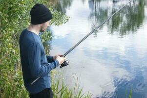 A lonely young guy goes fishing in the warm season. photo