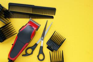 Hair clipper close-up on a yellow background with nozzles of different sizes, scissors and combs. photo