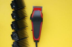 Hair clipper close-up on a yellow background with nozzles of different sizes. photo