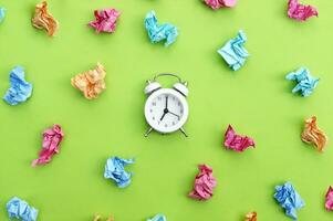 Vintage white alarm clock on a background of crumpled multicolored stickers. photo