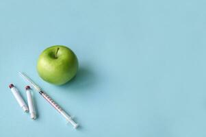 Green apple and syringe with GMO on a blue background. photo