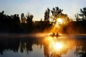 Two fisherman in a boat silhouette. photo