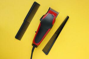 Hair clipper close-up on a yellow background with combs. photo
